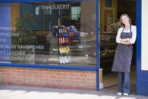 Woman Standing In Doorway Of Restaurant Smiling